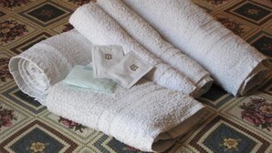 A set of neatly folded white towels on a patterned carpet. - Double or Twin Room (Catania)