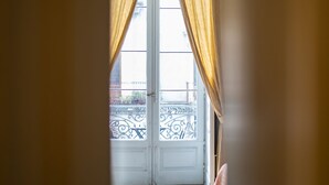 A view through a doorway with a curtain, leading to a balcony with a metal railing. - Family room (Catania)