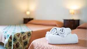 A hotel room with two beds, each with a different patterned bedspread. - Family room (Catania)