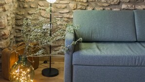 A room with a stone wall, a blue sofa, a floor lamp, and a decorative painting.
