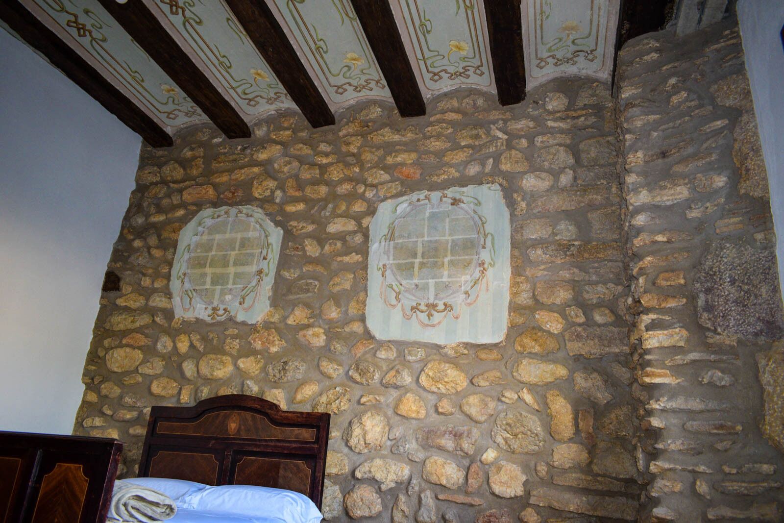 Un muro de piedra con un cabecero y estructura de cama de madera.