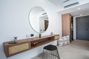 A modern reception area with a large mirror, a wooden console, a black stool, and a door leading to a closet.