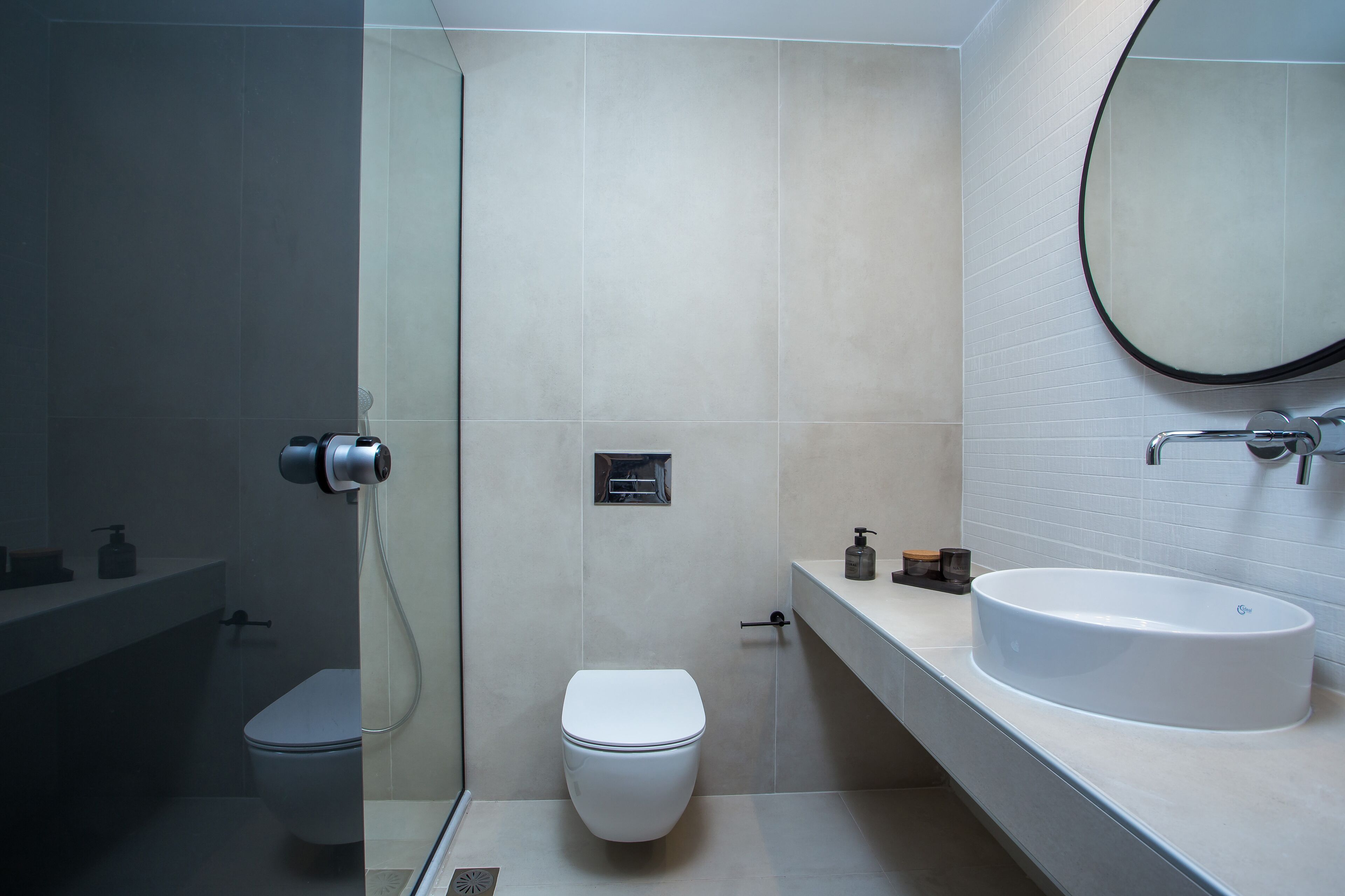 A modern bathroom with a toilet, a shower, and a sink.
