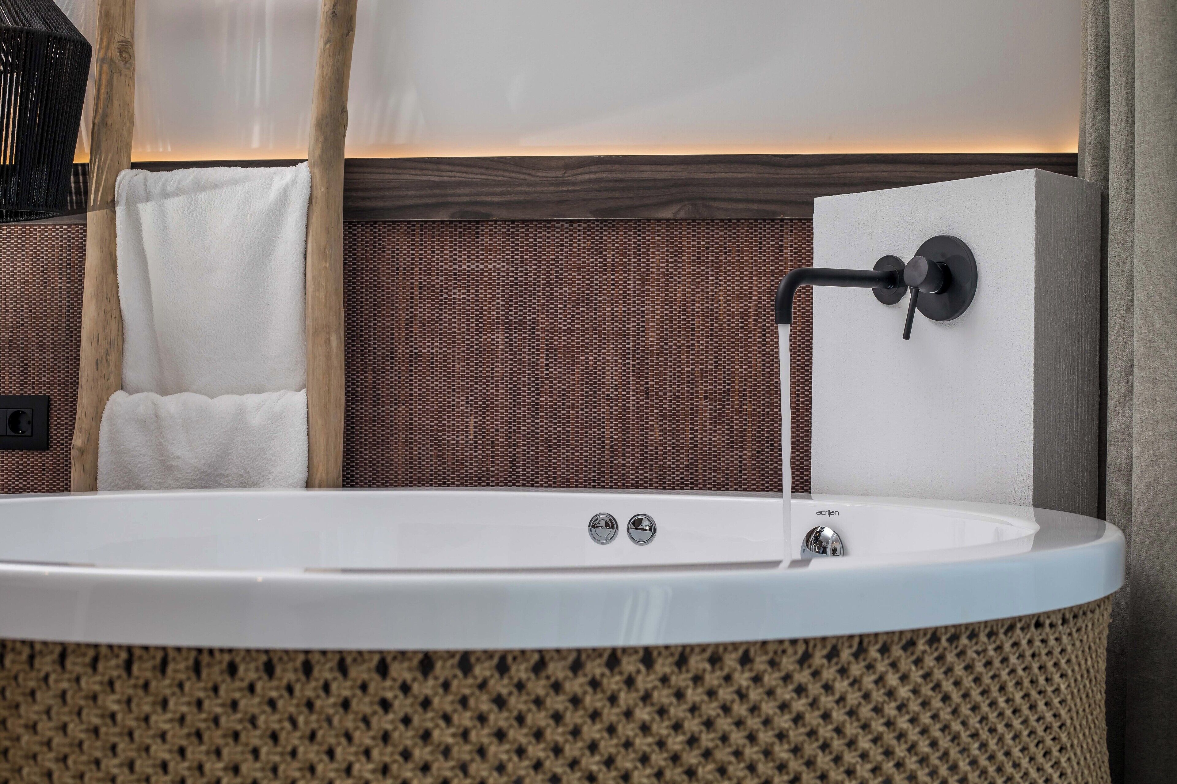 Un baño moderno con una bañera independiente, un perchero y una pared con textura.