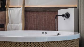 Un baño moderno con una bañera independiente, un perchero y una pared con textura.