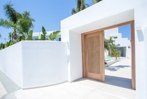 A modern building with a white exterior, a wooden door, and a clear sky.