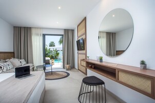 A modern hotel room with a bed, a desk, a chair, a TV, and a large mirror.