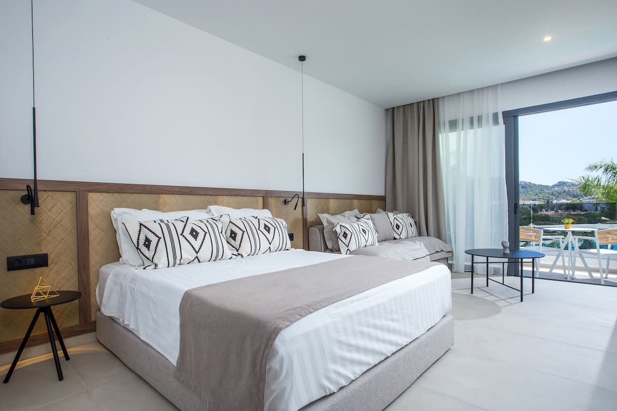 Una habitación de hotel moderna con una cama grande, una mesita pequeña y vistas al exterior.