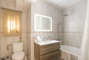 Een bad/douchecombinatie, een haardroger, zeep, toiletpapier