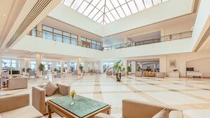 A spacious lobby with a high ceiling, a central coffee table, seating area, and a staircase connecting two floors. - SUNRISE Alma Bay Resort (Hurghada)
