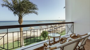 A balcony with wicker furniture, a glass table, and a view of the beach and ocean. - SUNRISE Alma Bay Resort (Hurghada)