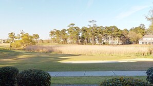 A golf course with a sand bunker, a pond, and a row of trees. - Tidewater Lighthouse 4113 (North Myrtle Beach)
