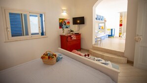 A bedroom with a bed, a red dresser, a TV, and a window with blinds. - Villa Olimpia 6 2 in Castellammare del Golfo (Castellammare del Golfo)
