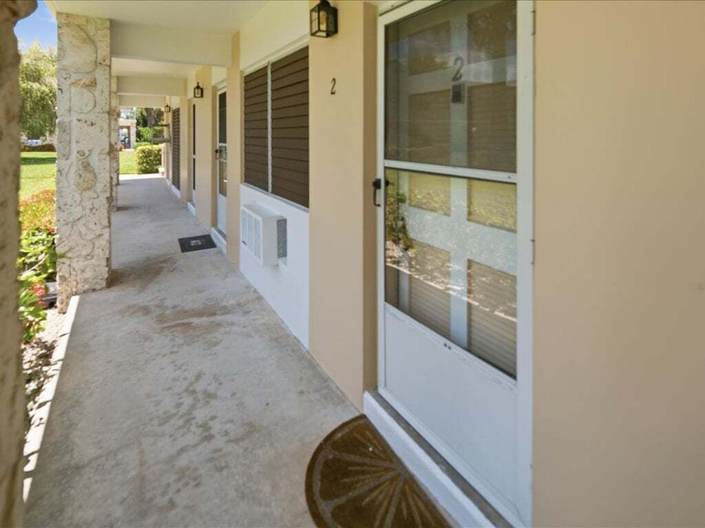 A covered porch with a stone column, a door with a number '2' sign, and a window with blinds.
