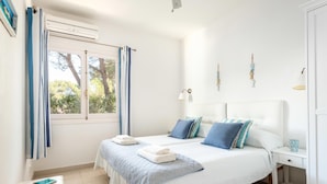 A bedroom with a bed, a nightstand, a bedside lamp, and a window with curtains. - Casa Aina - Four Bedroom Villa, Sleeps 8 (Son Parc)
