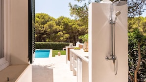 A modern outdoor shower area with a pool in the background. - Casa Aina - Four Bedroom Villa, Sleeps 8 (Son Parc)