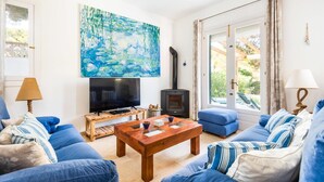 A living room with a TV, a fireplace, and a painting. - Casa Aina - Four Bedroom Villa, Sleeps 8 (Son Parc)