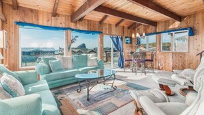 Un'ampia zona giorno con soffitto in legno, ampie finestre e vista sul paesaggio.