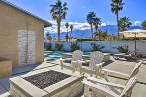 A patio with Adirondack chairs, a fire pit, and a pool.