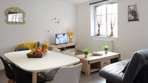 A modern living room with a white table, black and yellow chairs, a wooden desk, and a grey sofa. - L'ombre Dieppoise - Dieppe (Dieppe)