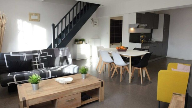 A modern living room with a sofa, coffee table, and dining area. - L'ombre Dieppoise - Dieppe (Dieppe)