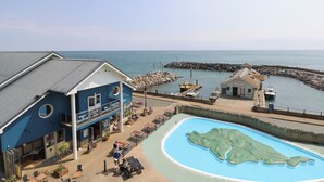 A coastal building with a pool, a cafe, and a lifeguard tower.