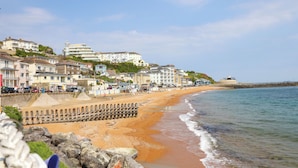 A coastal town with a sandy beach, a promenade, and buildings along the shore.