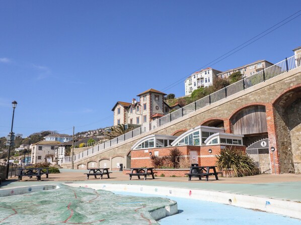 A coastal promenade with picnic tables, a swimming pool, and a stone bridge. - No. 5 Cliffview (Ventnor)