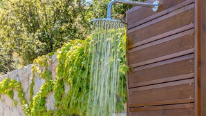 A shower with a stone wall and wooden paneling. - 31 Blue - Aqua Blue - Private Infinity Pool and BBQ Area (Apolpena)