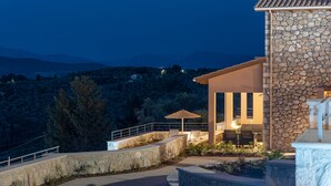 A stone building with a balcony, outdoor seating, and a view of the surrounding landscape. - 31 Blue - Aqua Blue - Private Infinity Pool and BBQ Area (Apolpena)