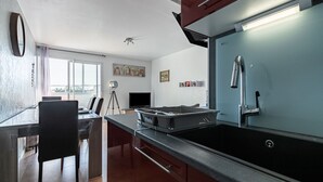 A modern kitchen with a large island, a built-in oven, and a stainless steel sink.