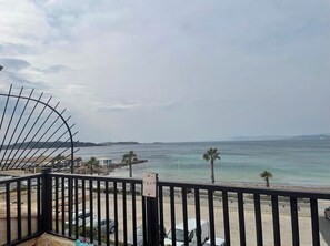 Ein Balkon mit Blick auf das Meer, Palmen und einen Parkplatz.