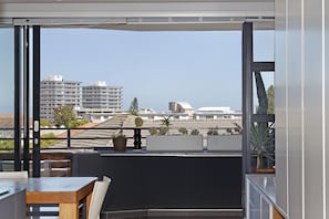 A balcony with a table and chairs, potted plants, and a view of buildings.