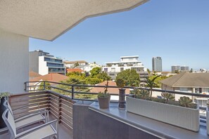 A balcony with a railing, potted plants, and a view of city buildings. - Nine On S 3E (Cape Town)
