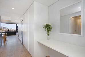 A modern kitchen with white cabinetry, a wooden dining table, and a vase with white flowers on a white shelf. - Nine On S 3E (Cape Town)