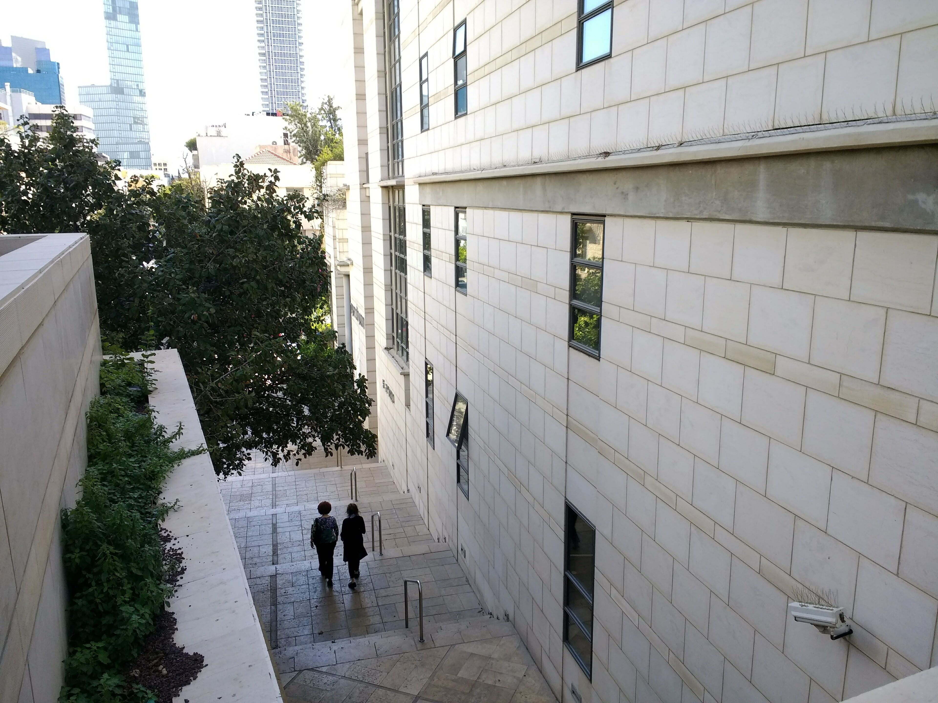 Un étroit chemin urbain bordé de bâtiments aux murs recouverts de carreaux et aux petites fenêtres.