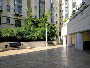 A courtyard with a bench, a lamppost, and a building with a modern design.