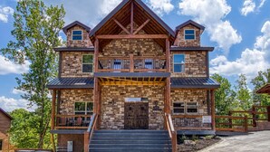 A two-story stone building with a wooden balcony, a central entrance, and a sign indicating it is a lodge.
