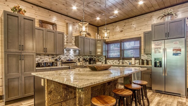 A modern kitchen with granite countertops, stainless steel appliances, and wooden bar stools.