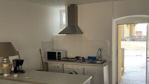 Moderni keittiö, jossa on keskeinen saareke, integroidut kodinkoneet ja suuri ikkuna.
