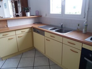 A kitchen with beige cabinets, a stainless steel sink, and a window with a view of greenery.