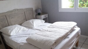 A neatly made bed with white bedding, a bedside table with a lamp, and a window with a view of greenery. - 4-bedroom house in the heart of the Abers (7-minute walk from Ganaoc beach) (Saint-Pabu)
