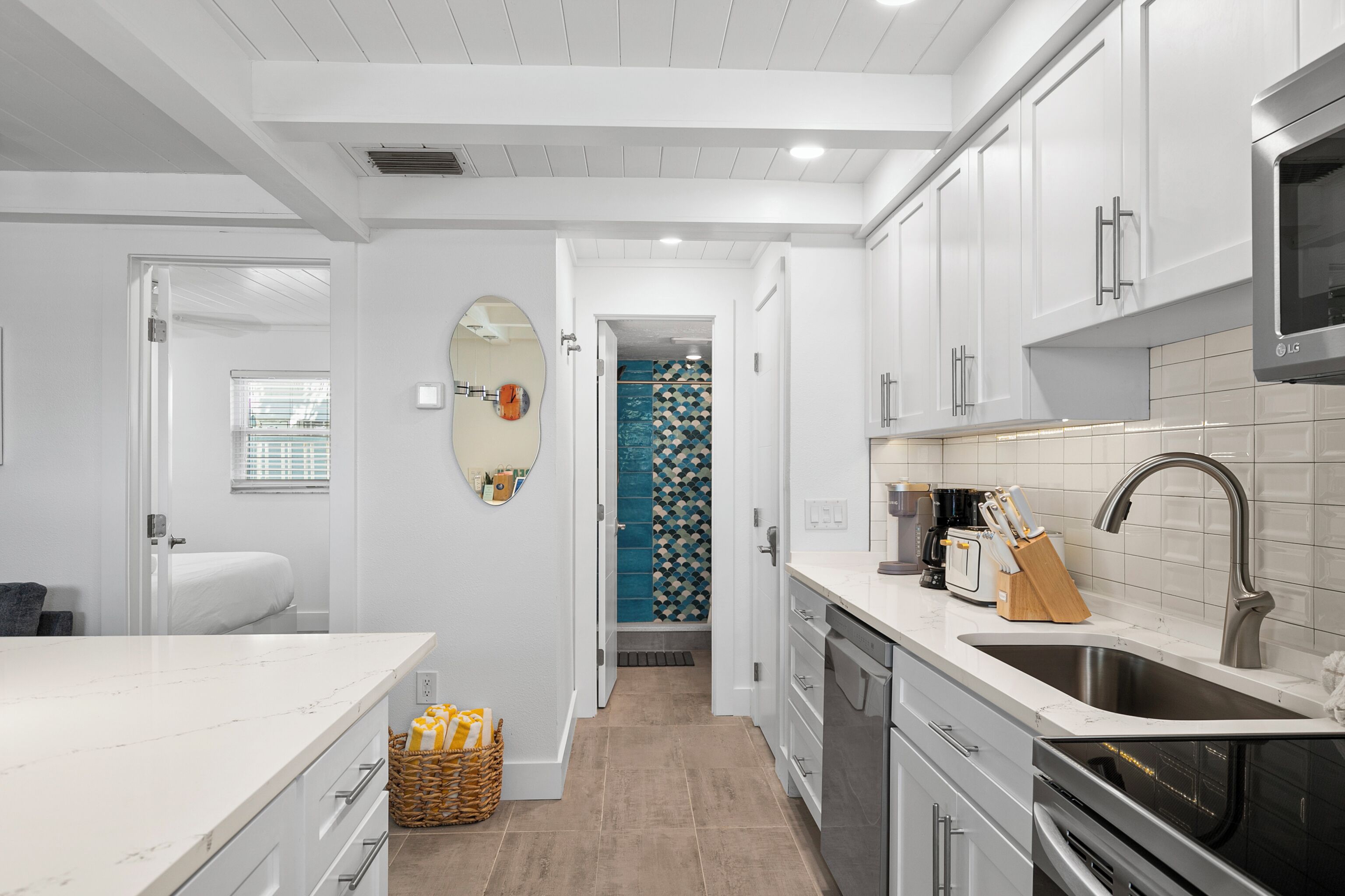 A modern kitchen with white cabinets, a stainless steel sink, and a built-in oven.