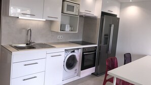Een moderne keuken met een roestvrijstalen koelkast, een inbouwoven, een magnetron en een wasmachine.