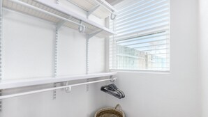 Un cuarto de lavado con estantes blancos, una cesta y una ventana con persianas.