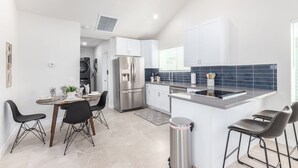 Una cocina moderna con armarios blancos, un refrigerador de acero inoxidable y un revoque de azulejos negros.