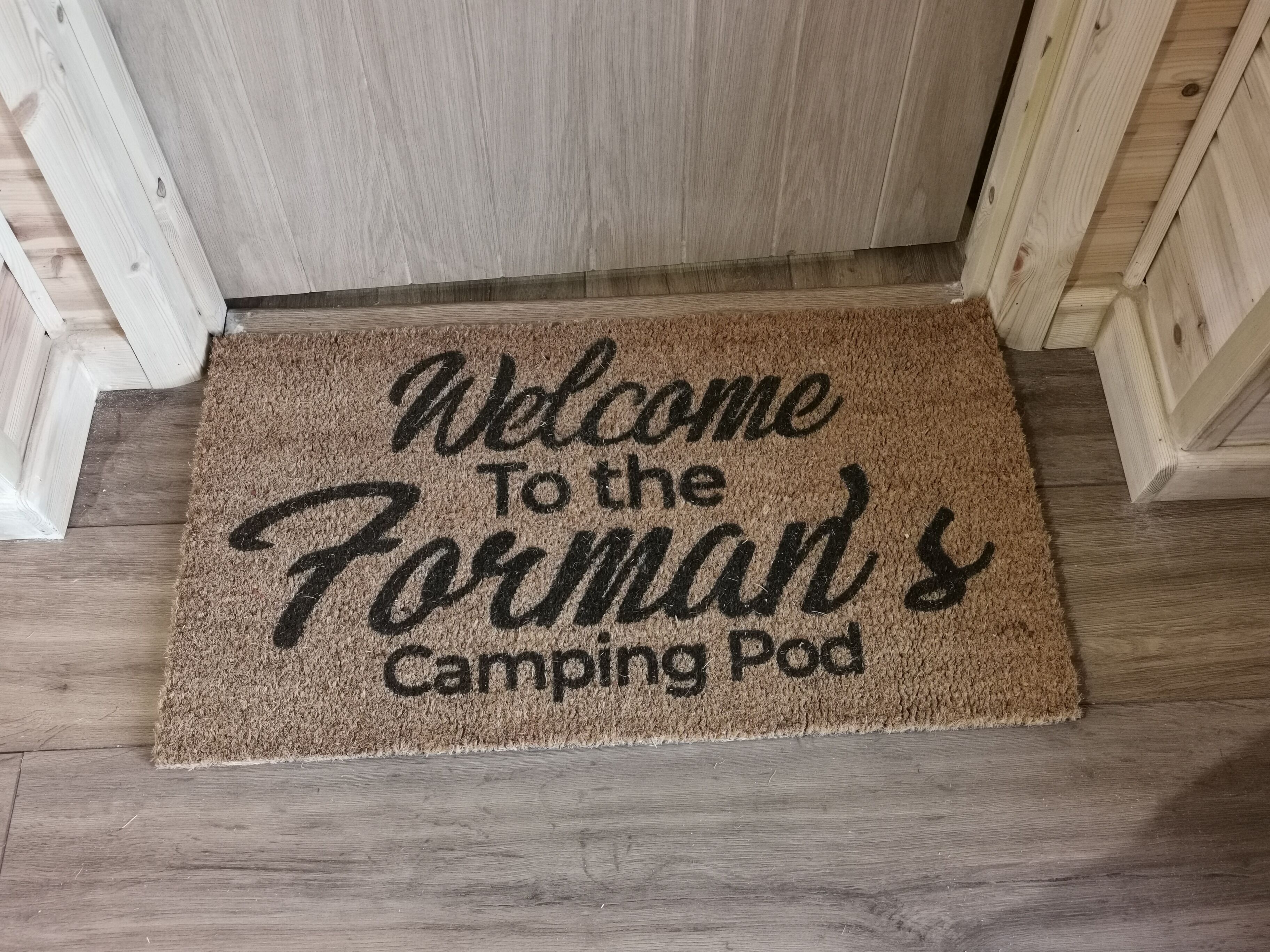 A welcome mat with the text "Welcome To the Forman's Camping Pod".