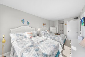 A bedroom with two beds, a nightstand, a lamp, and decorative items.