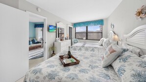 Une chambre avec deux lits, une télévision, une commode et une fenêtre donnant sur un beau paysage.