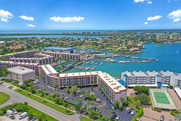 A coastal hotel with multiple buildings, a marina, and a road leading to the property.